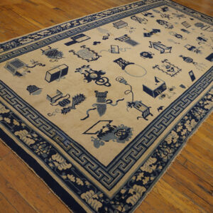 Low-pile beige rug with dark and light blue scattered patterns and ornate borders on wood flooring.