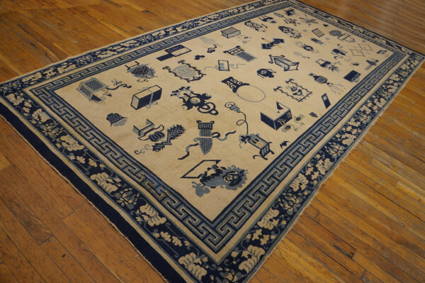 Low-pile beige rug with dark and light blue scattered patterns and ornate borders on wood flooring.
