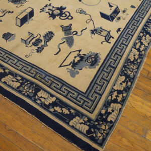 A cream rug featuring scattered blue objects and complex navy floral and geometric borders on wood planks.