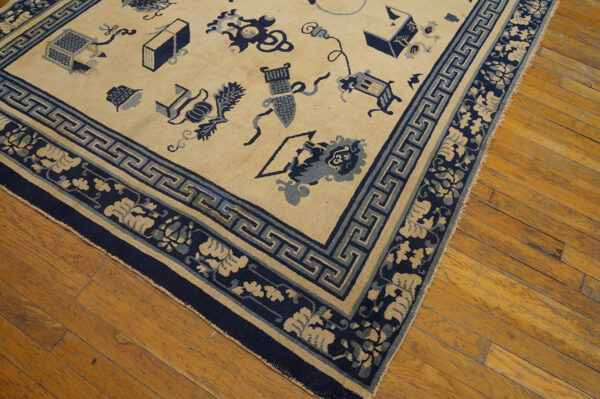 A cream rug featuring scattered blue objects and complex navy floral and geometric borders on wood planks.