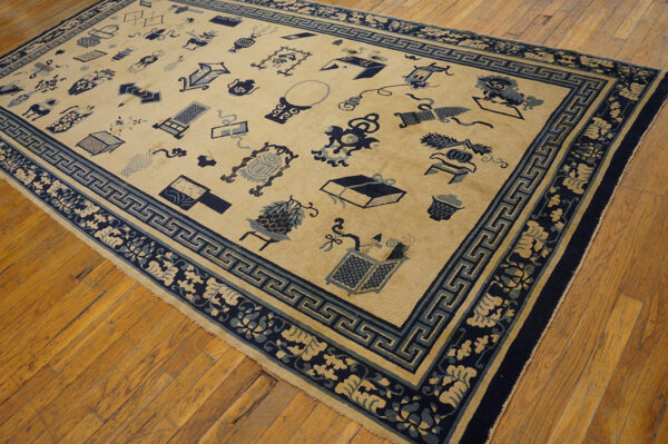 Traditional tan rug featuring dark and light blue symbolic patterns and geometric borders on a wood floor.