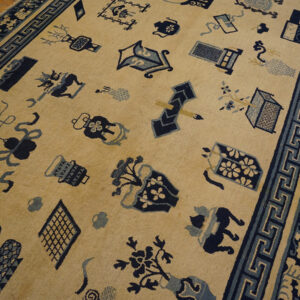 Tan low pile rug featuring scattered navy and light blue object motifs, resting on hardwood flooring.