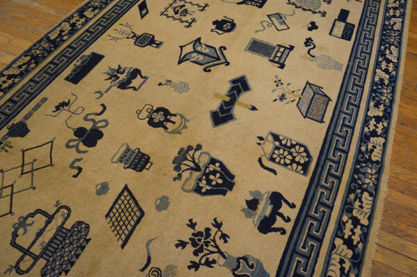 Tan low pile rug featuring scattered navy and light blue object motifs, resting on hardwood flooring.