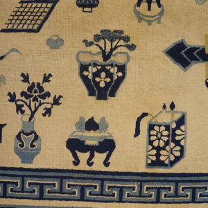 Cream field rug with scattered navy and light blue artifact motifs and a prominent Greek key border.