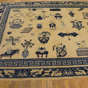 Low-pile cream and blue rug with scattered object patterns and Greek key borders on light wood flooring.
