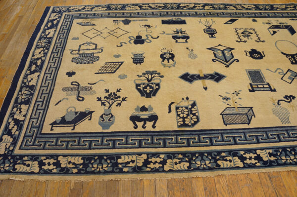 Low-pile cream and blue rug with scattered object patterns and greek key borders on light wood flooring.