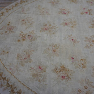 Oval cream rug featuring a faded floral pattern of blush pink and beige roses on light wood flooring.