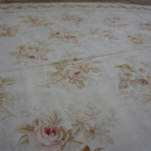 Low-pile oval rug with pale pink and tan floral bouquets scattered across a cream background.