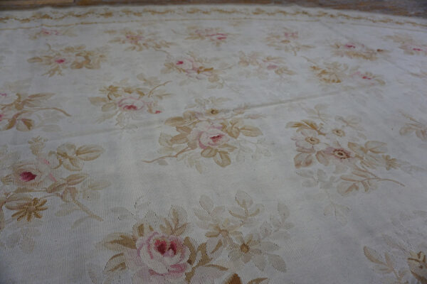 Low-pile oval rug with pale pink and tan floral bouquets scattered across a cream background.