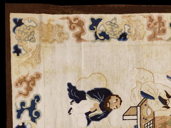 Medium pile cream rug corner detail showing traditional figures and cloud shapes in blue, tan, and brown.