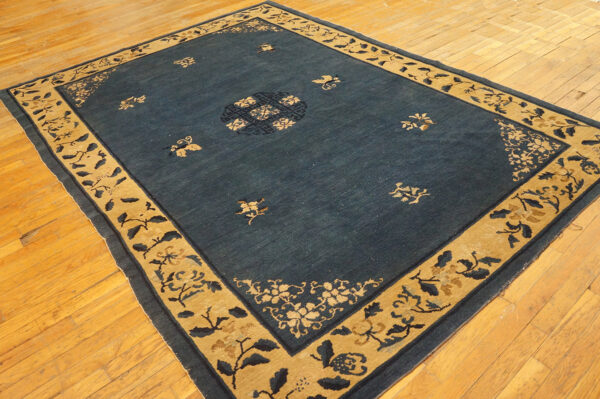 Wool hand knotted pile rectangle antique blue ivory beige cream white 1920s rug 3 Deep blue rug with a wide gold border and floral patterns rests on light hardwood floors.
