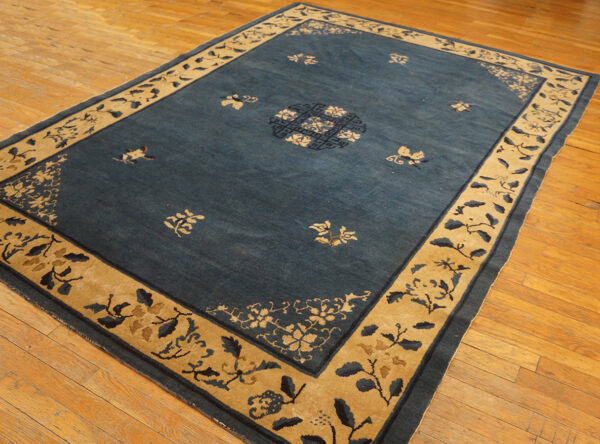 Wool hand knotted pile rectangle antique blue ivory beige cream white 1920s rug 4 Dark blue rug with a wide tan border and floral patterns lies on varnished hardwood flooring.