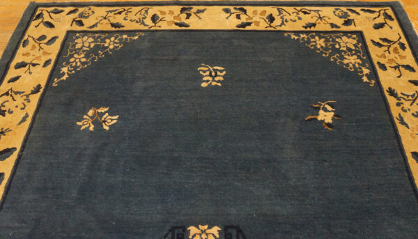 Wool hand knotted pile rectangle antique blue ivory beige cream white 1920s rug 10 Dark blue low-pile rug featuring a wide tan border with intricate floral spandrel and central motifs on wood flooring.