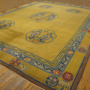 Gold rug with blue and red dragon medallions and geometric borders rests on worn wooden flooring.