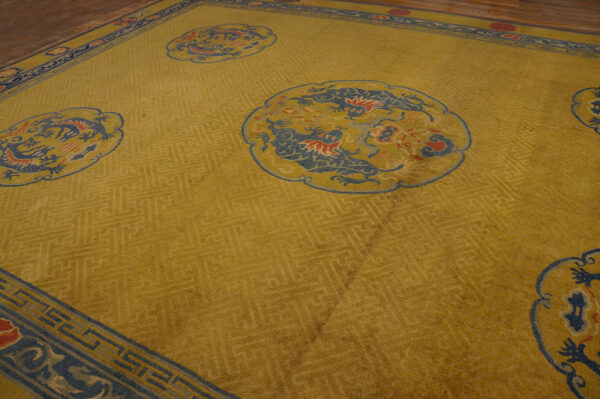 Mustard yellow rug featuring blue and red dragon motifs inside scalloped medallions and a dark blue border.