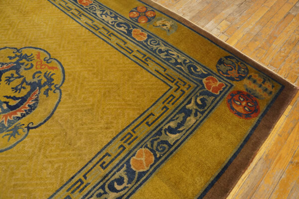 Mustard yellow rug featuring complex blue and terracotta patterned borders on worn wood planks.