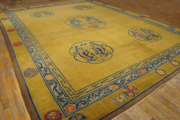 Gold-yellow area rug with five blue dragon medallions and a wide blue and orange ornamental border on wood flooring.