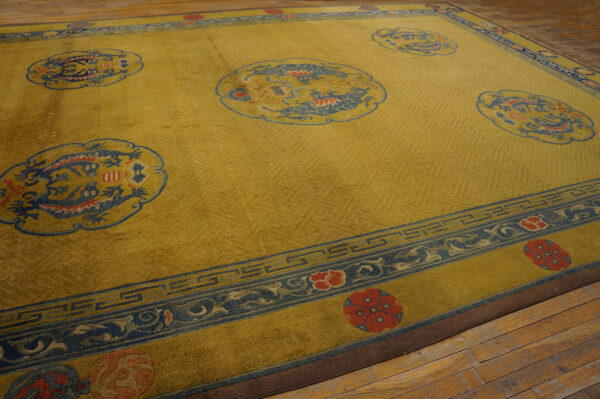 Golden yellow rug with tone-on-tone fretwork, large blue dragon medallions, and blue floral borders on wood flooring.