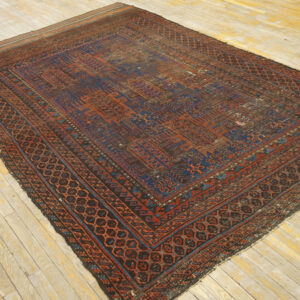 Low-pile rug with geometric patterns in deep red and indigo blue on rustic wooden planks.