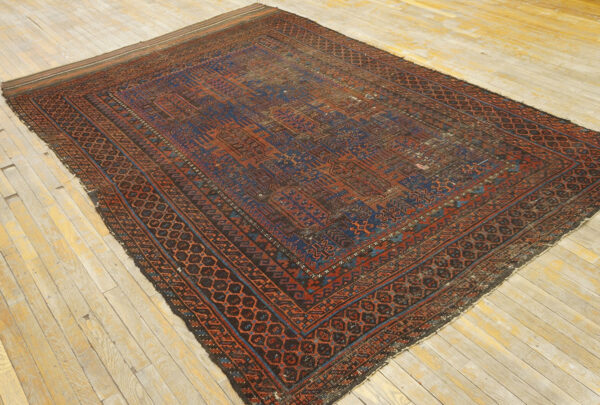 Low-pile rug with geometric patterns in deep red and indigo blue on rustic wooden planks.