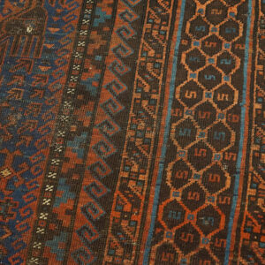 Geometric patterns in rust and blue cover the dark low-pile rug lying on light hardwood planks.