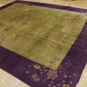 High-pile rug in olive green with a wide plum border patterned with branches and birds on a wood floor.