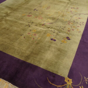 Olive green rug with delicate pink and yellow florals features a deep purple border on light hardwood floors.