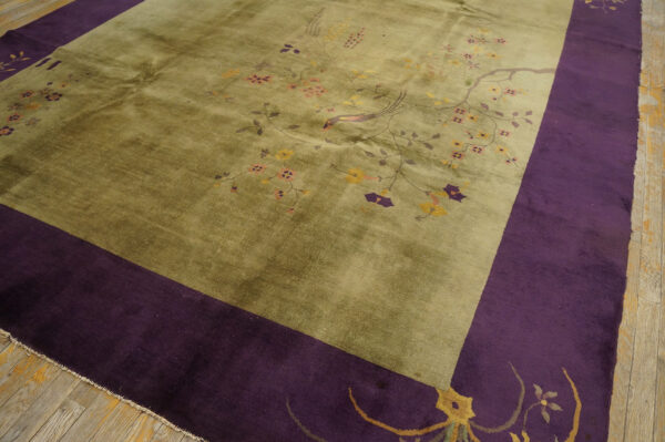 Olive green rug with delicate pink and yellow florals features a deep purple border on light hardwood floors.