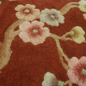 Terracotta rug detail showing raised floral pattern in pale pink, cream, and green.