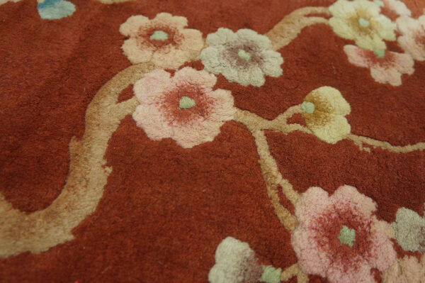 Terracotta rug detail showing raised floral pattern in pale pink, cream, and green.