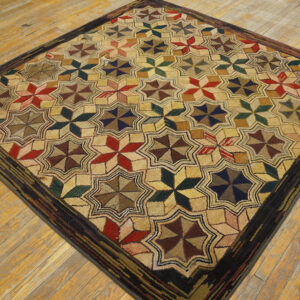 Hooked square rug with multicolored star patterns and a wide dark border rests on rustic hardwood floors.