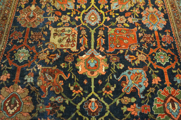 Intricate traditional rug pattern featuring tight knots and worn texture in teal, rust, navy, and pink.