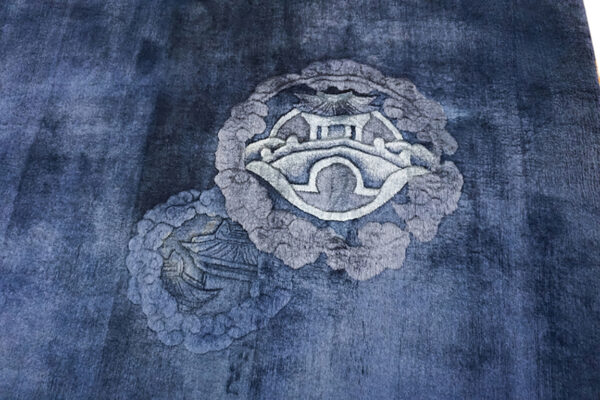 Deep blue pile rug featuring carved dragon designs and light fringe on glossy hardwood flooring.