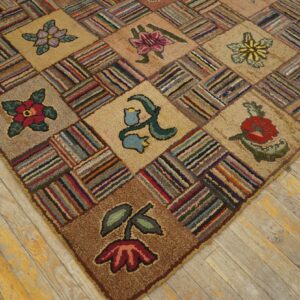 Close-up view of a textured, multicolored patchwork rug with floral patterns on aged wood floors.