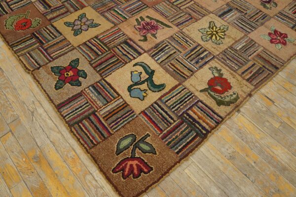 Close-up view of a textured, multicolored patchwork rug with floral patterns on aged wood floors.