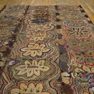 High-texture, multicolored floral and wavy patterned rug displayed on yellow wooden floorboards.
