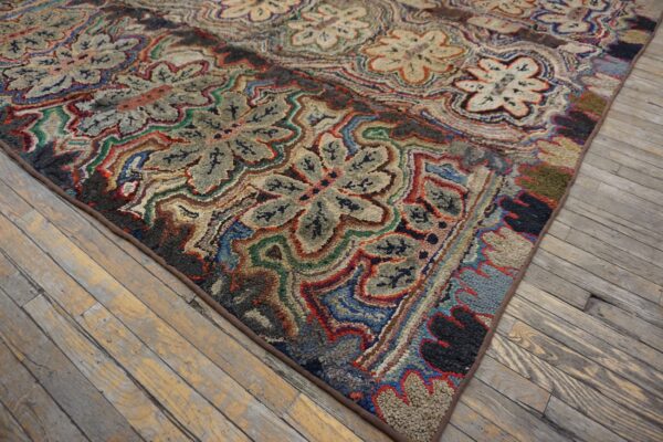 Intricate red, blue, green, and gray hooked rug featuring large floral medallions on worn wood floors.