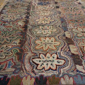 Multicolored hooked rug with large stylized floral patterns on light natural wood flooring.