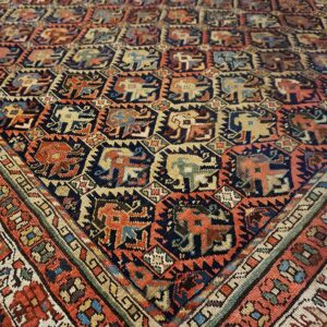Close-up of a tribal rug featuring repeated stylized animal figures in navy, terracotta, and cream colors.