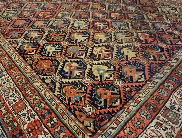 Close-up of a tribal rug featuring repeated stylized animal figures in navy, terracotta, and cream colors.
