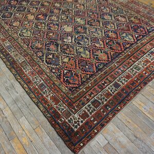 Muted navy and rust geometric rug with intricate borders lies on distressed wood planks.