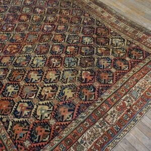 Stylized animal motifs cover this navy and rust low-pile rug lying on weathered wood plank flooring.