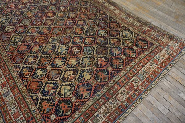 Stylized animal motifs cover this navy and rust low-pile rug lying on weathered wood plank flooring.
