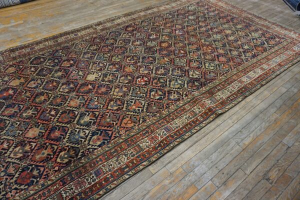 Multicolored rug with a dense geometric pattern and complex borders rests on distressed, gray wooden planks.