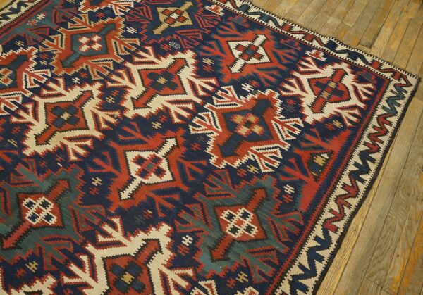 Geometric flatweave rug featuring navy, terracotta, cream, and green patterns, resting on wood flooring.