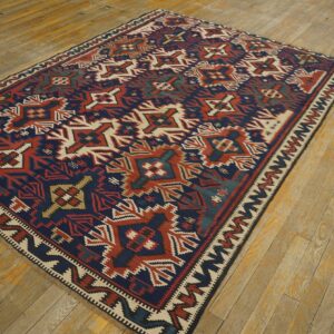 Flatweave rug with large geometric motifs in navy, rust red, and cream on worn wood floors.