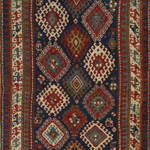 Low-pile rug with a deep navy field and dense tribal patterns in red, cream, and slate blue.