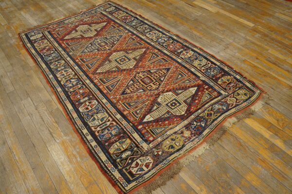 A geometric rug featuring rust, blue, and cream patterns lies on rustic wooden flooring.