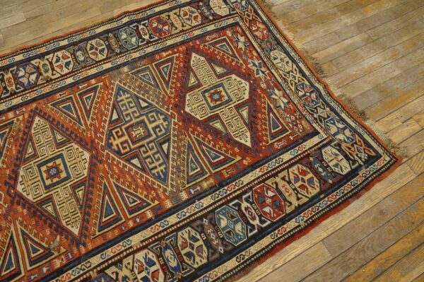 A low-pile geometric rug in rust, navy, and tan rests upon rustic wooden plank flooring.