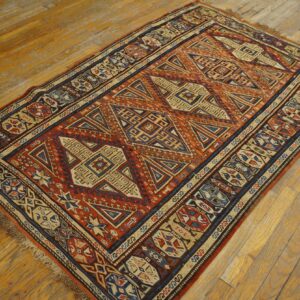 Geometric area rug featuring rust, navy, and tan patterns on rustic hardwood floors.